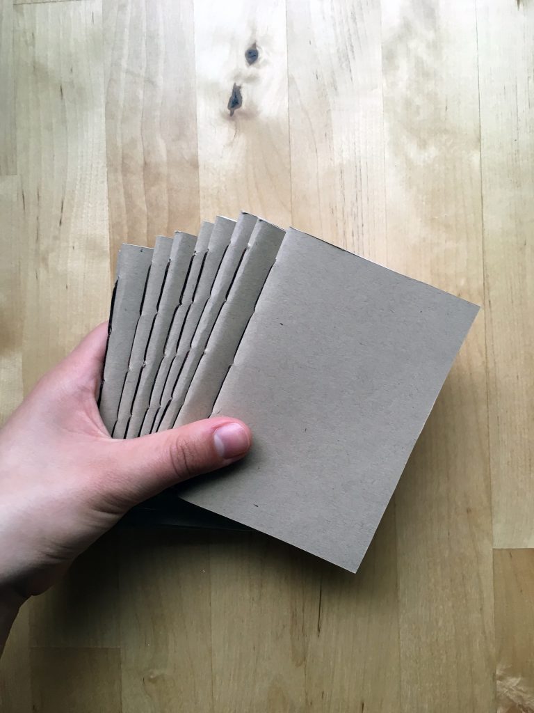 A hand holding some handmade notebooks
