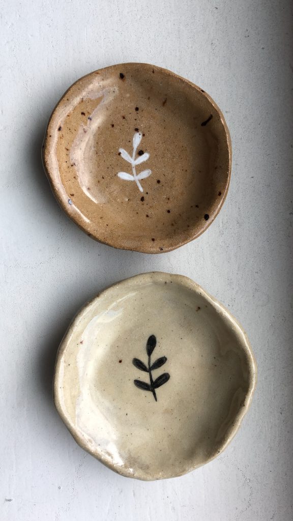 Two small handmade dishes with small branch illustrations painted on