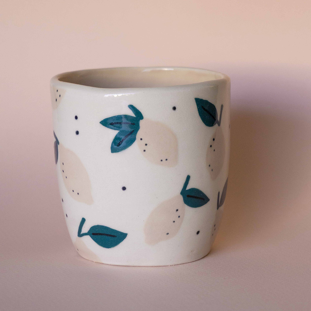 A ceramic mug with pink lemons painted on it