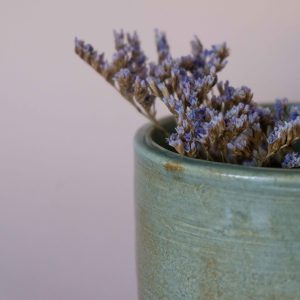 A closeup of a ceramic mug with lavender sprigs inside it