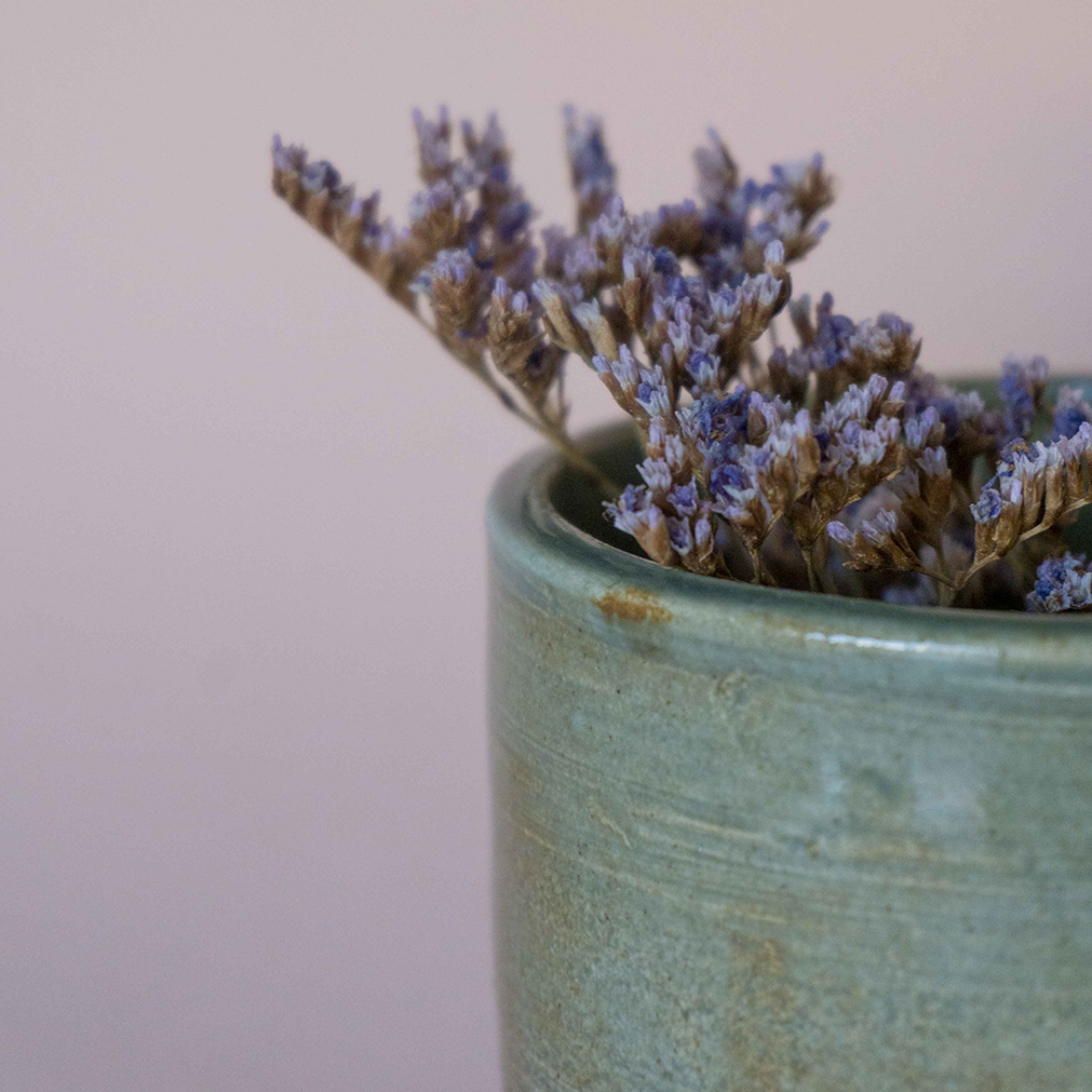 A closeup of a ceramic mug with lavender sprigs inside it